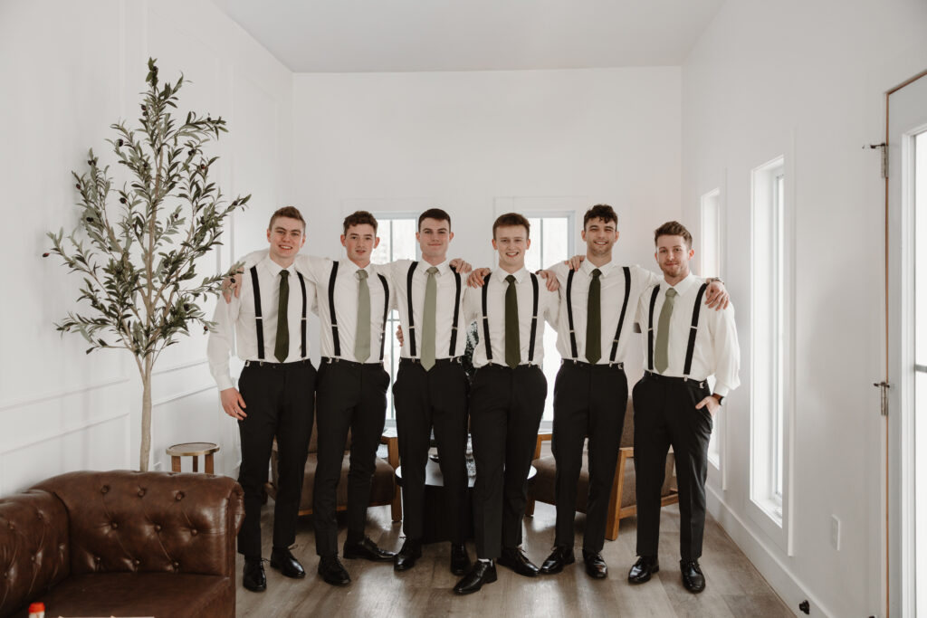 Groom and groomsmen smiling while getting ready for winter wedding at Grand Ivory in Cognac Suite