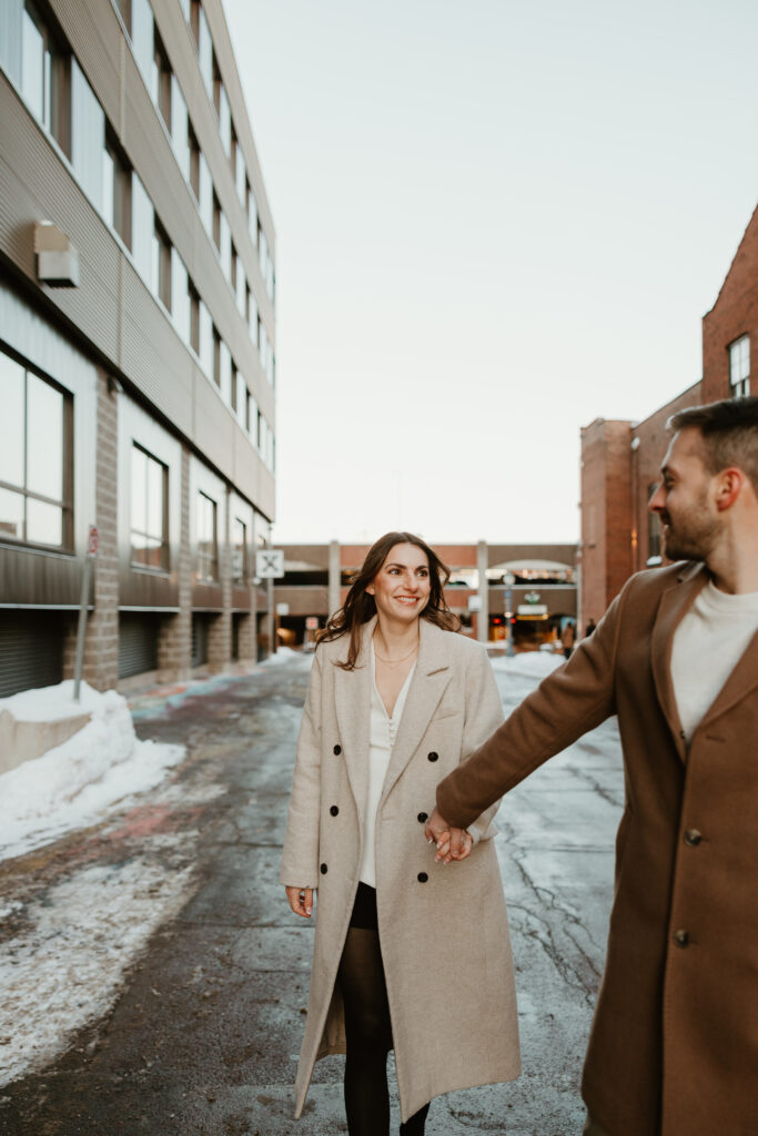 man leading women in downtown streets during engagement pictures