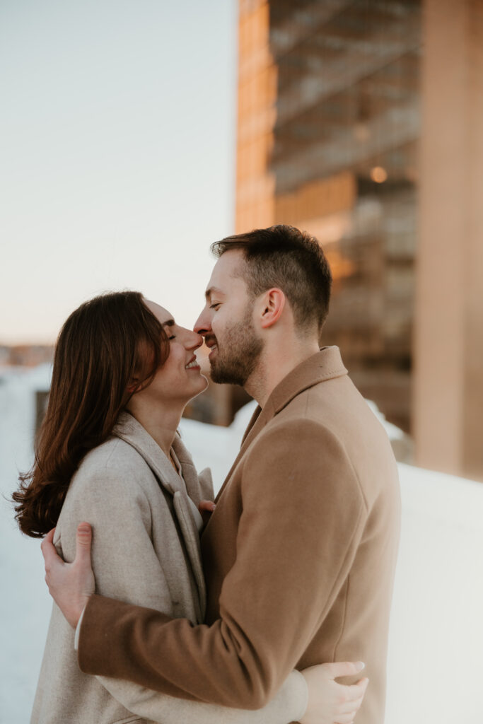 couple nose to nose almost kissing outside during winter engagement photoshoot
