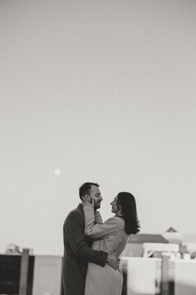couple on top of parking garage gazing at each other with moon in background