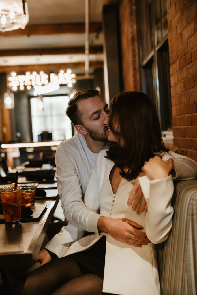 bar engagement session couple kissing at table