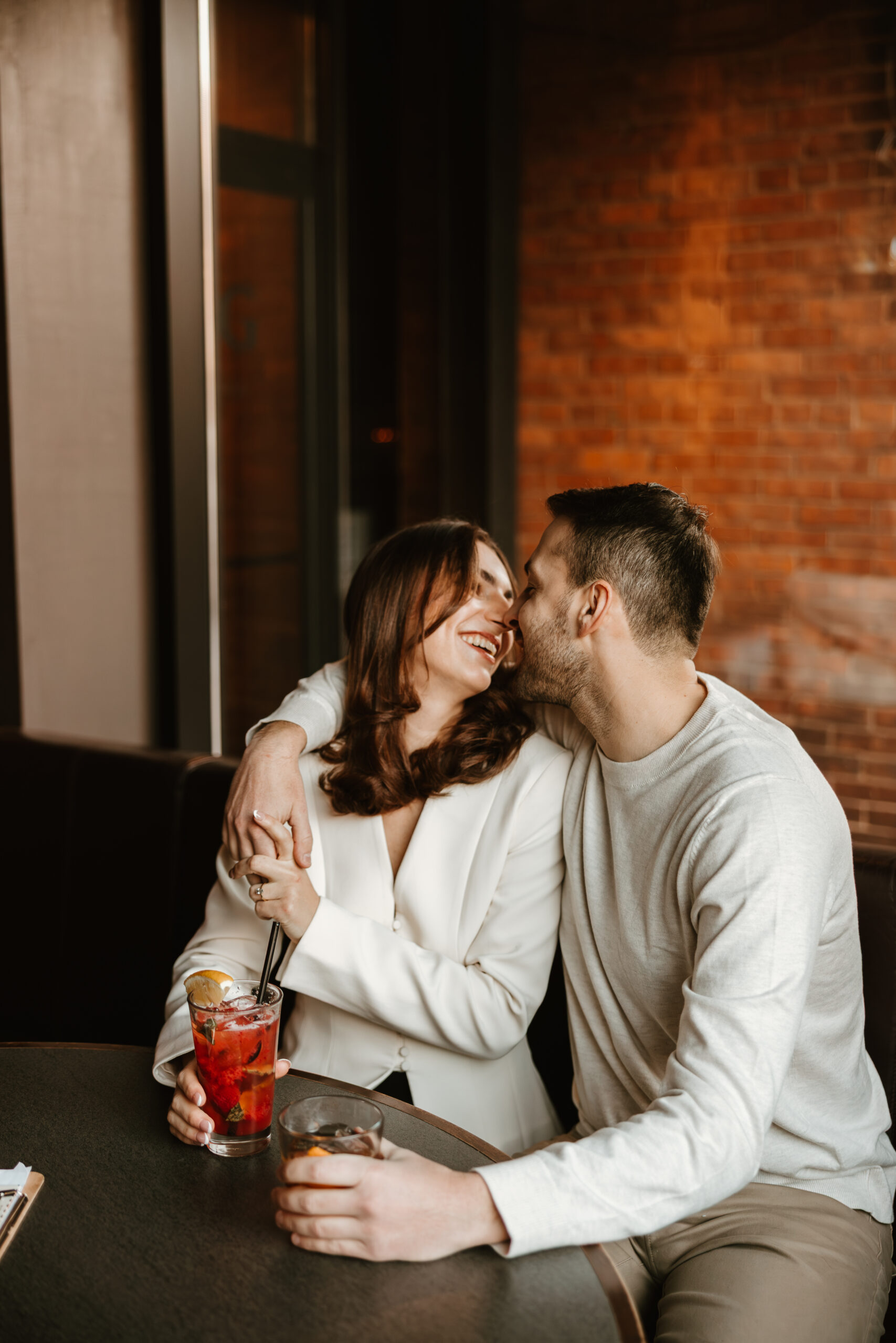 downtown bar engagement session couple kissing at table