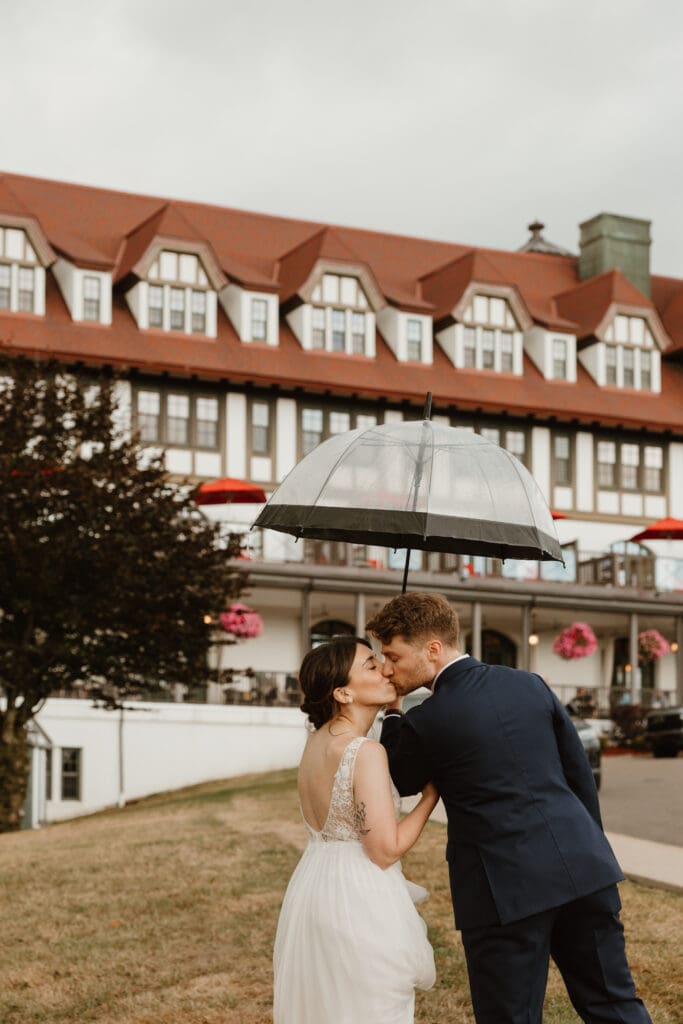 Bride and groom kissing in the rain in front of the Algonquin