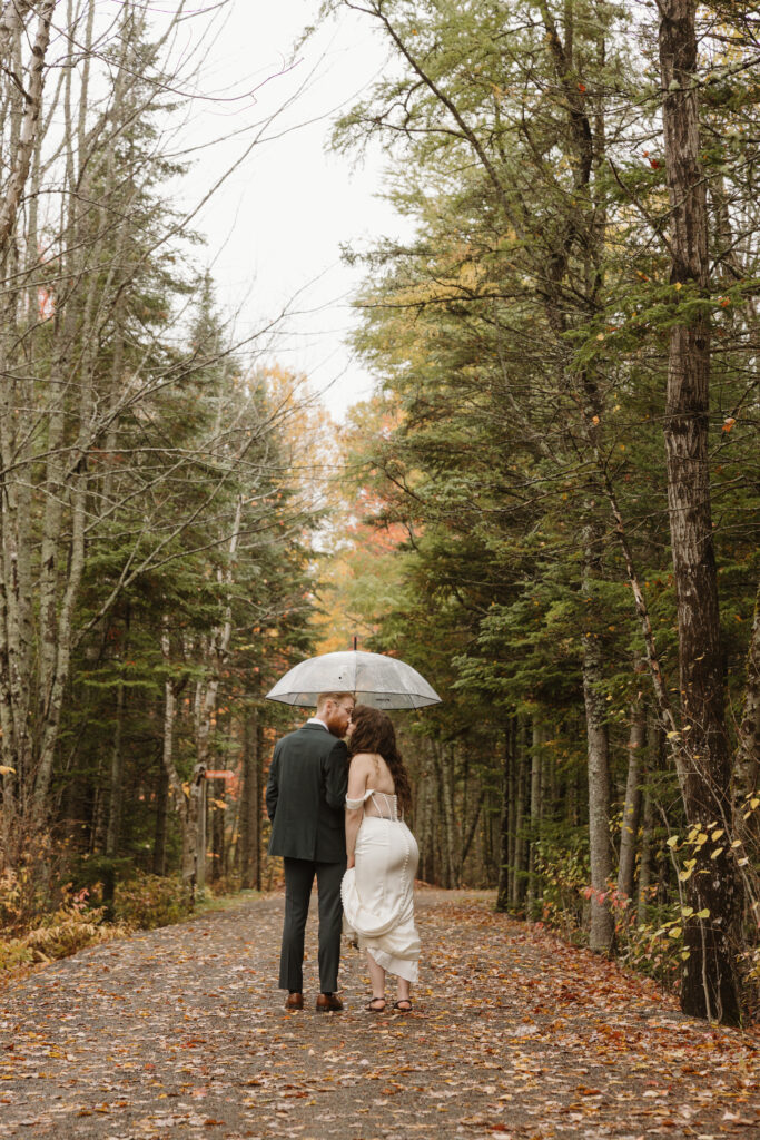 bride and groom exchanging a kiss under a clear umbrella at irishtown park