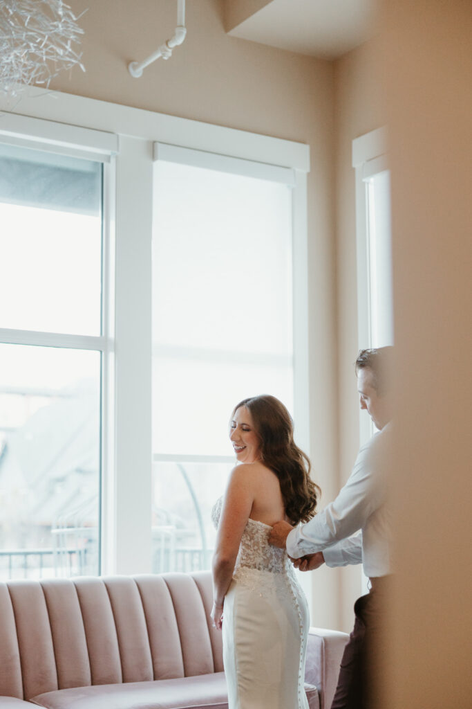Groom zipping bride dress at Banff Alberta elopement