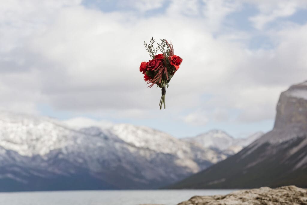 Lake Minnewanka elopement bouquet toss with mountains in background